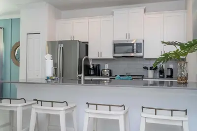 a kitchen with white cabinets and a counter with stools at NEW to Market 5 Bed - Storey Lake Retreat in Kissimmee