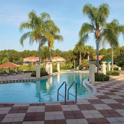 a swimming pool with palm trees in a resort at Private Pool Townhome at Encantada Resort in Kissimmee