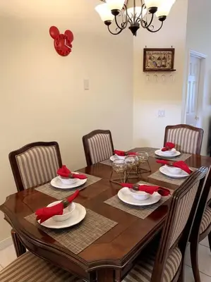 a dining room table with chairs and a wooden table with red napkins at Minutes to Disney! Spacious Home w/ Private Pool, Themed Rooms! in Orlando