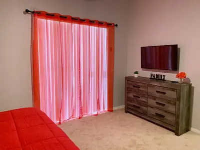 a bedroom with a television and a red curtain at Minutes to Disney! Spacious Home w/ Private Pool, Themed Rooms! in Orlando