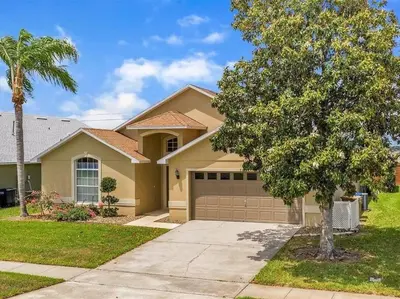 a house with a tree and a garage at Minutes to Disney! Spacious Home w/ Private Pool, Themed Rooms! in Orlando