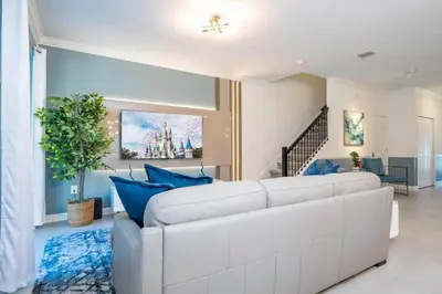 a living room with a white couch and blue pillows at Wonderful 5 Bd w Pool @ Storey Lake Resort 2545 in Kissimmee