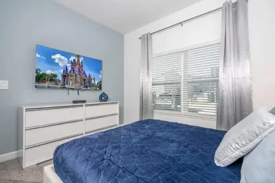 a bedroom with a blue bed and a window at Wonderful 5 Bd w Pool @ Storey Lake Resort 2545 in Kissimmee