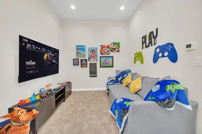 a living room with a gray couch and a flat screen tv at Magical Themed Home Near Disney in Orlando