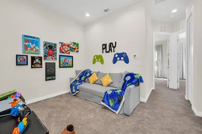 a living room with a gray couch and some pictures at Magical Themed Home Near Disney in Orlando
