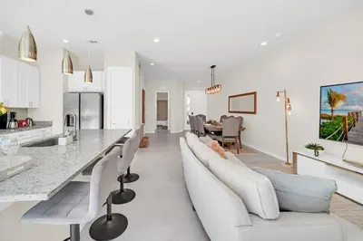 a kitchen and living room with white furniture and a table at Magical Themed Home Near Disney in Orlando