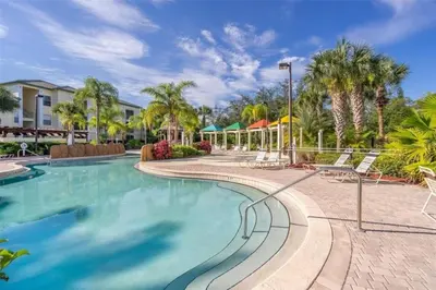 a swimming pool at a resort with chairs and trees at LD8830-12-308DC - Legacy Dunes condo for 8 guests in Kissimmee