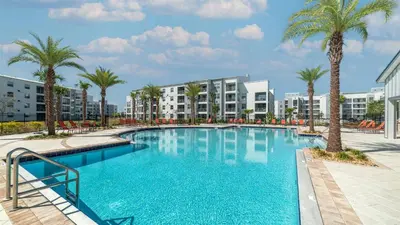 a large swimming pool with palm trees and buildings at 3151 Paradox #306 in Kissimmee