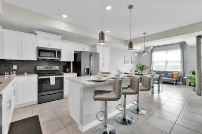 a kitchen with white cabinets and a kitchen island with bar stools at 3151 Paradox #306 in Kissimmee