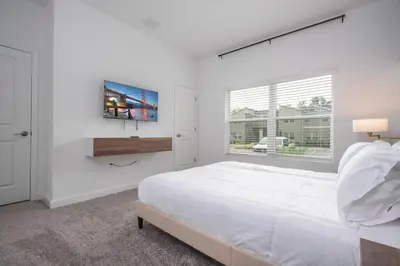 a white bedroom with a large bed and a window at Brand New Cozy Retreat at Storey Lake Resort in Kissimmee