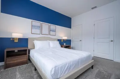 a bedroom with a large bed and a blue wall at Brand New Cozy Retreat at Storey Lake Resort in Kissimmee