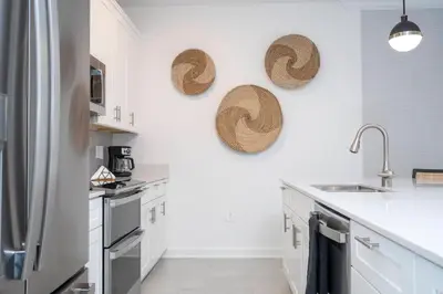 a kitchen with white cabinets and straw hats on the wall at Brand New Cozy Retreat at Storey Lake Resort in Kissimmee