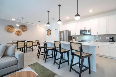 a kitchen and living room with a bar and chairs at Brand New Cozy Retreat at Storey Lake Resort in Kissimmee