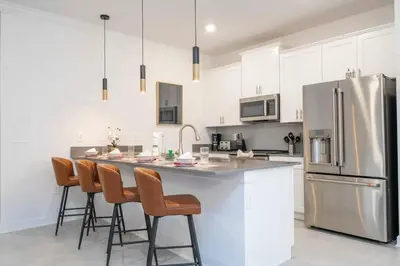 a kitchen with white cabinets and a stainless steel refrigerator at Stunning 5 Bd w Pool at Storey Lake Resort 2400 in Kissimmee