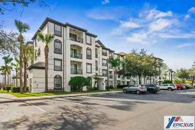 an apartment building with cars parked in a parking lot at The Epic Edinburgh Top Floor Vista Cay Orlando in Orlando