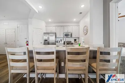 a kitchen with white cabinets and a table and chairs at The Epic Edinburgh Top Floor Vista Cay Orlando in Orlando