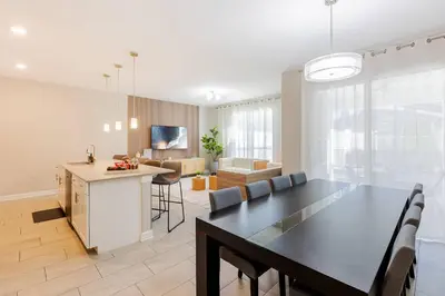a kitchen and living room with a black table and chairs at Family 4BR w Private Pool near Disney Parks in Kissimmee