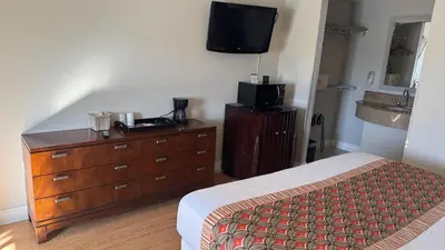 a bedroom with a bed and a dresser with a television at Hotel Monte Carlo in Kissimmee