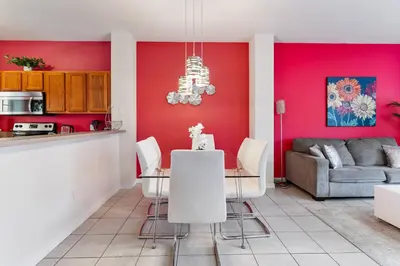 a kitchen and living room with a red wall at Amazing 3Bdrms At Encantada- 6 miles from Disney in Kissimmee