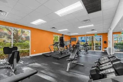 a gym with rows of tread machines and orange walls at Amazing 3Bdrms At Encantada- 6 miles from Disney in Kissimmee