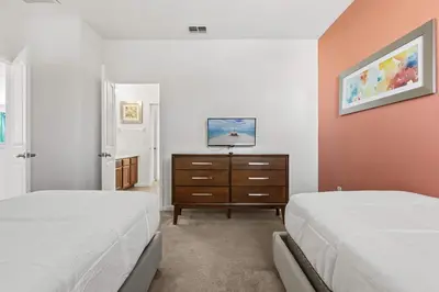 a bedroom with two beds and a dresser with a tv at Sunny Stay in Orlando - 6BR Home with Pool! in Kissimmee