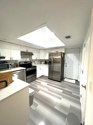 a kitchen with white cabinets and a stainless steel refrigerator at House close Baldwin-park Lake & Downtown Orlando in Orlando