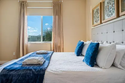 a bedroom with a bed with blue pillows and a window at 4 BR Home w/ Resort Amenities + 3 Mi to Disney in Orlando