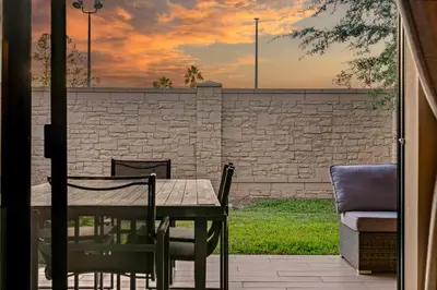 a table and chairs on a patio with a brick wall at Outdoor Kitchen + 8 Min to Disney + Resort Cabanas in Orlando