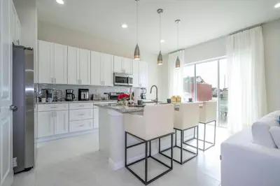 a kitchen with white cabinets and a kitchen island with bar stools at New Exclusive Villa 5 min to Disney in Orlando