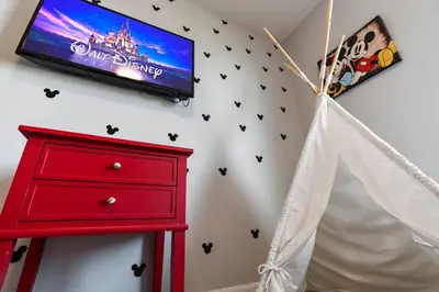 a bedroom with a red dresser and a tv on a wall at Amazing 4BdrmsPrivate Hot Tub7 miles from Disney in Kissimmee