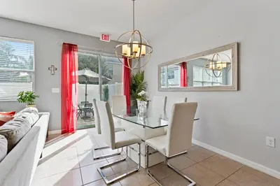 a dining room with a glass table and white chairs at Amazing 4BdrmsPrivate Hot Tub7 miles from Disney in Kissimmee