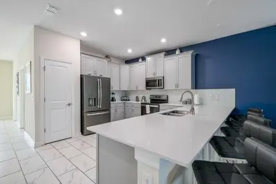a kitchen with white cabinets and a blue wall at Charming Home Ideal Location Spacious Game Room in Kissimmee