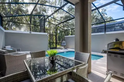 a patio with a glass table and a swimming pool at Luxury Chic Modern Home Prime Location in Kissimmee