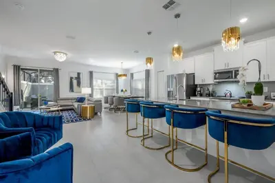 a kitchen and living room with blue bar stools at Luxury Chic Modern Home Prime Location in Kissimmee