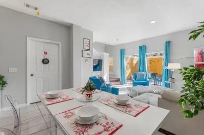 a living room with a table and blue chairs at Serene Stay at Terra Verde Resort by Shine Villas 111 townhouse in Kissimmee