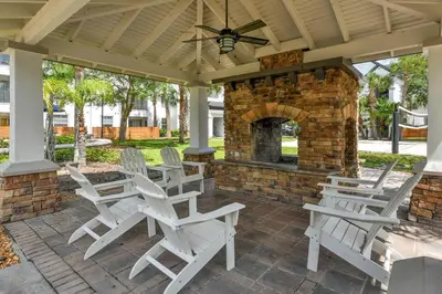 a patio with white chairs and a stone fireplace at Orlando Retreat 2B2B / Disney-Universal-SeaWorld in Orlando