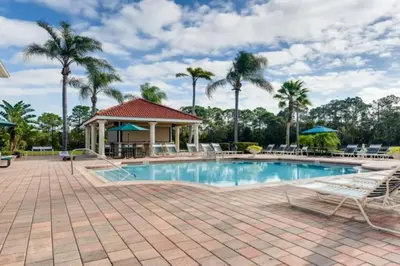 a pool at a resort with chairs and palm trees at Lakefront 6BR Resort Pool Home Near Disney in Kissimmee