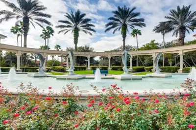 a fountain in a garden with palm trees in the background at Lakefront 6BR Resort Pool Home Near Disney in Kissimmee
