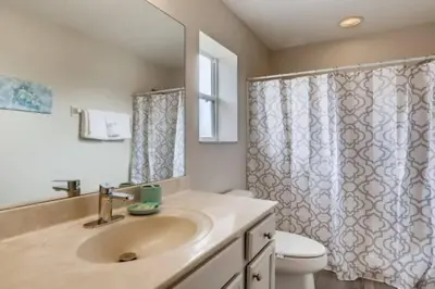 a bathroom with a sink and a toilet and a mirror at Lakefront 6BR Resort Pool Home Near Disney in Kissimmee