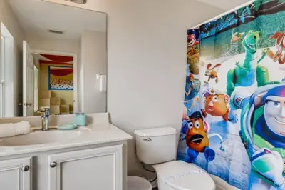 a bathroom with a toilet and a large painting on the wall at Lakefront 6BR Resort Pool Home Near Disney in Kissimmee