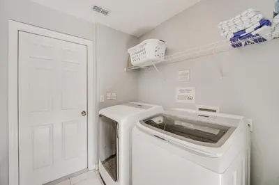 a white laundry room with a washer and dryer at 7 Mi to Disney Kissimmee Home with Pool and Hot Tub! in Kissimmee