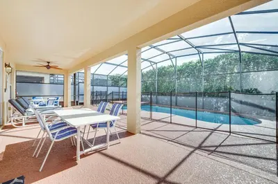 a glass house with a swimming pool and a table and chairs at 7 Mi to Disney Kissimmee Home with Pool and Hot Tub! in Kissimmee