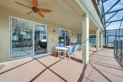 a porch with a ceiling fan and a table and chairs at 7 Mi to Disney Kissimmee Home with Pool and Hot Tub! in Kissimmee