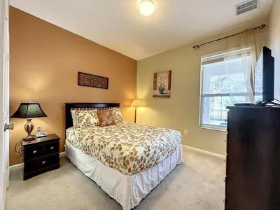 a bedroom with a bed and a window and a television at This amazing 6 Bedroom property with a lake view in Orlando