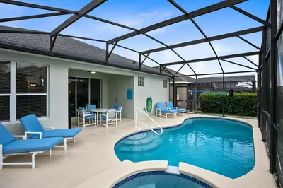 a patio with a swimming pool with chairs and a table at Immaculate 4 bedrooms 3 bathroom in Windsor Palms in Kissimmee