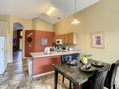 an open kitchen and dining room with a table at Emerald Island Resort 4 bed 3 bath with pool/spa in Kissimmee