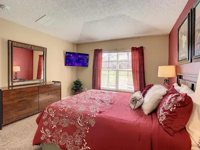 a bedroom with a red bed and a large window at Emerald Island Resort 4 bed 3 bath with pool/spa in Kissimmee