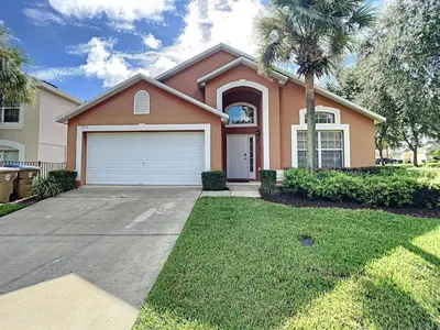 a house with a palm tree and a garage at Emerald Island Resort 4 bed 3 bath with pool/spa in Kissimmee