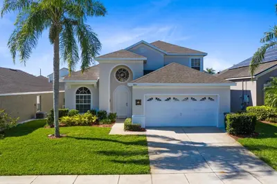 a house with a palm tree and a garage at Fantastic Resort 5BR House - South Facing Pool/Spa in Kissimmee
