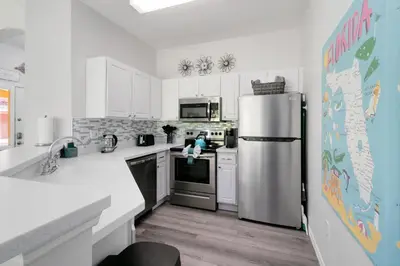 a kitchen with white cabinets and a stainless steel refrigerator at Disney Area 4 bed/ 3.5 Bathroom Emerald Island in Kissimmee